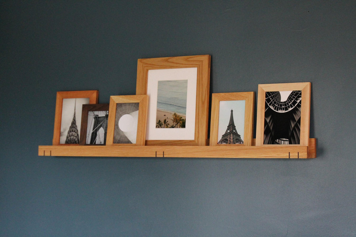 White oak 3-inch ledge shelf with a row of framed city and beach prints on a blue wall