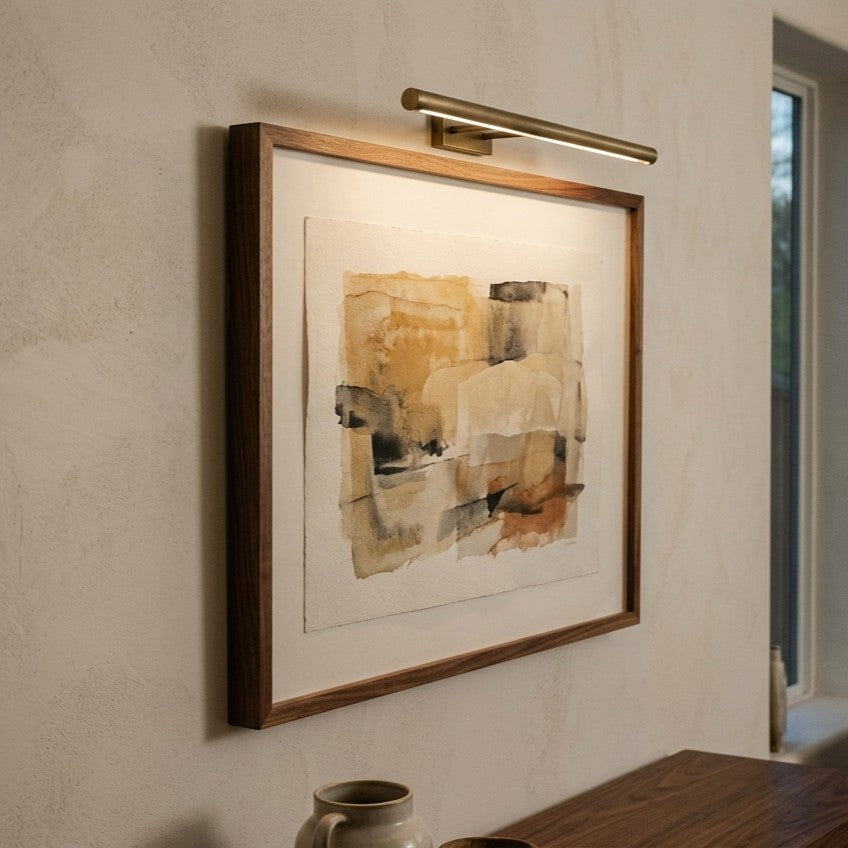 Brass picture light above an abstract painting in a walnut frame