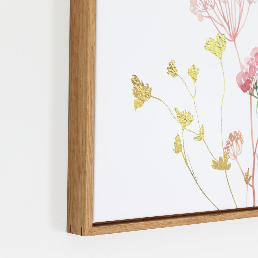 Corner of a solid hardwood frame with a spline joint, around a gold and pink botanical print