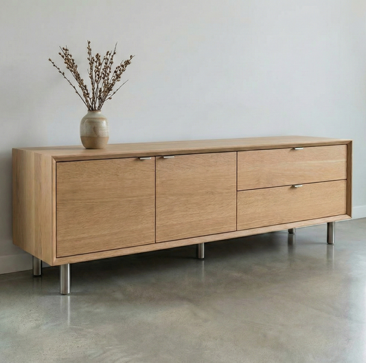 Wooden sideboard with three drawers and a vase with branches on a plain wall background