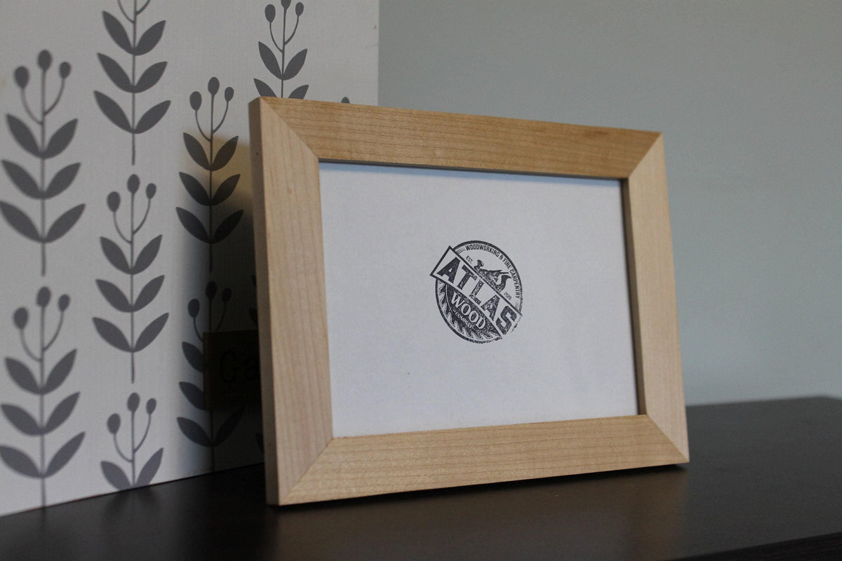 Maple 4 x 6 desktop frame on a dark tabletop in front of a leaf-pattern backdrop
