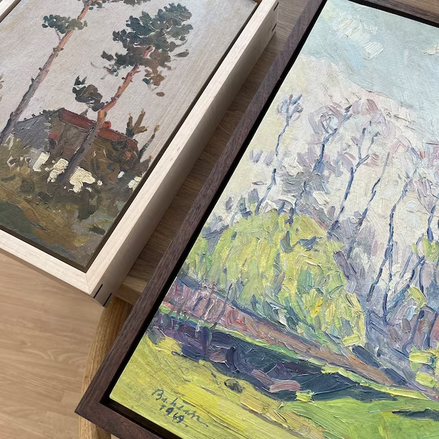 a couple of paintings sitting on top of a wooden table