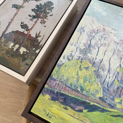 a couple of paintings sitting on top of a wooden table