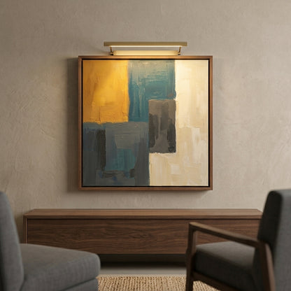 Abstract framed wall art hanging above a wooden console in a modern living room, with a wall sconce above the frame. The artwork features large blocks of mustard yellow, teal, gray, and cream.