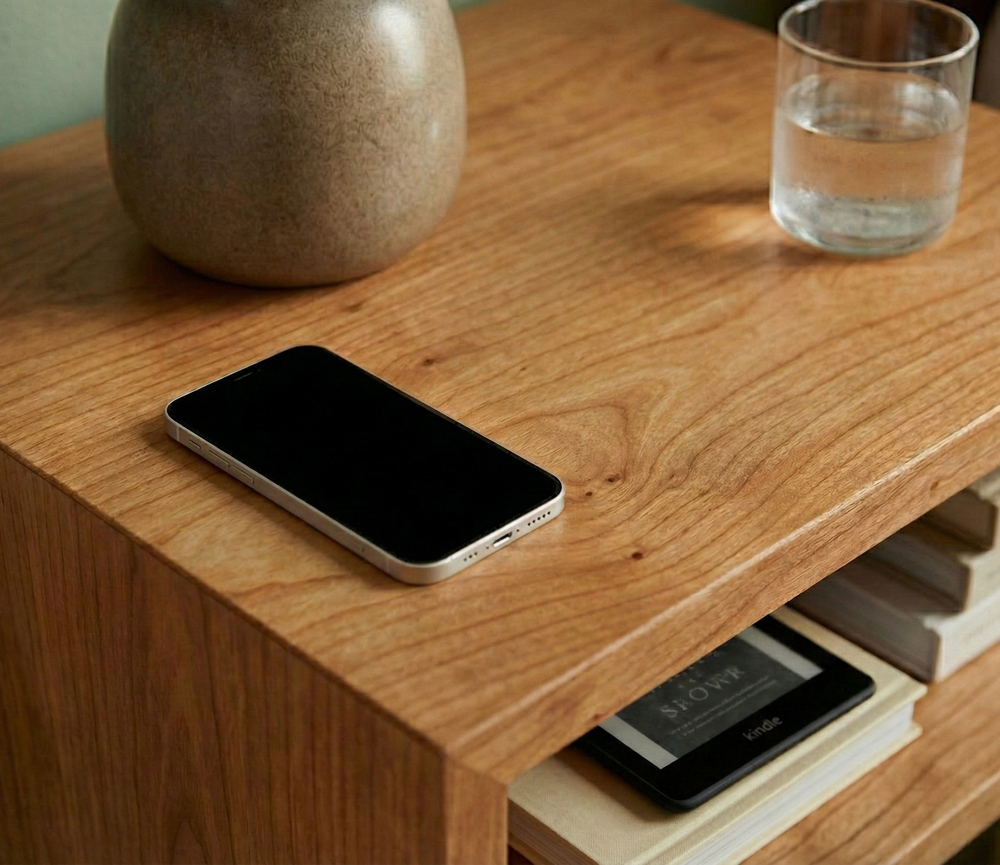 Smartphone on a wooden surface with a glass of water and a vase in the background