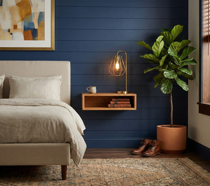 Modern bedroom with blue wall, bed, nightstand, and plant