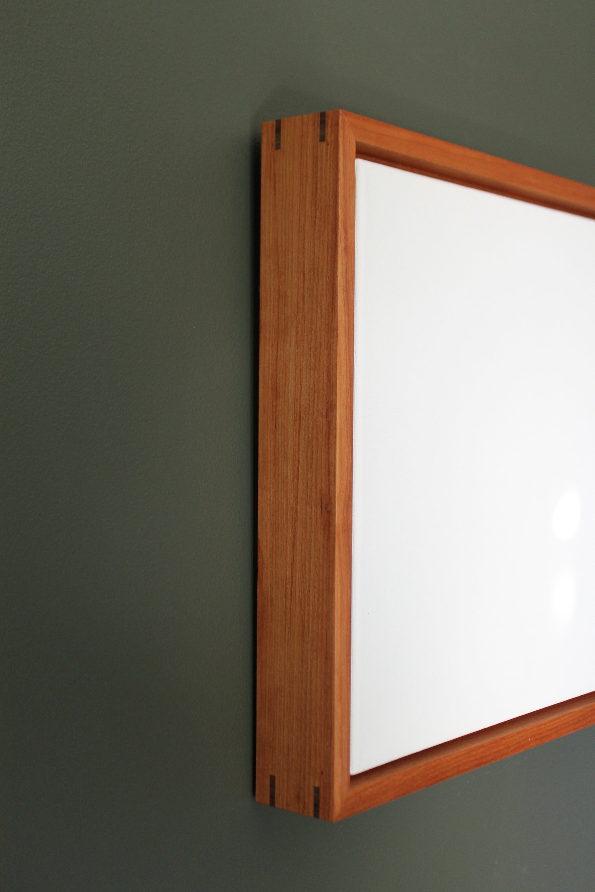 a mirror mounted on a wall with a wooden frame